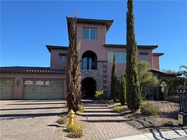 Two-story house with stucco exterior, three-car garage, and landscaped yard at 8490 Via De Bellasidra Ct, Las Vegas, NV 89123