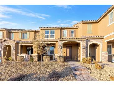 Tan two-story townhome with stone accents, landscaping, and a paved walkway at 3296 Palindrome Ave, Henderson, NV 89044