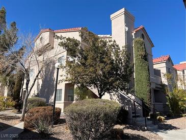 Two-story stucco building with Spanish-style architecture, landscaping, and a walkway at 5225 W Reno Ave # 129, Las Vegas, NV 89118