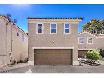 Tan two-story house with brown garage door and front landscaping at 1425 Bow Creek Ct, Las Vegas, NV 89128