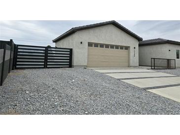Modern home exterior featuring a two-car garage and a gravel driveway at 1760 Ironside Street St, Pahrump, NV 89048