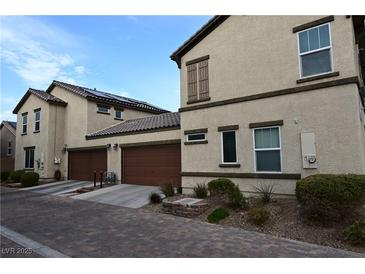 Tan two-story home with solar panels, attached garage, and landscaped yard at 1055 Admiral Emblem St, Henderson, NV 89015