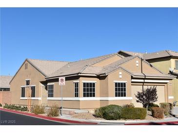 Tan one-story house with a two-car garage and landscaped yard at 304 Whitney Breeze Ave, North Las Vegas, NV 89031