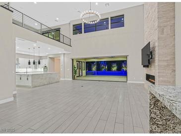 Open-concept living area with a fireplace and large sliding doors leading to the pool at 65 Garibaldi Way, Henderson, NV 89011