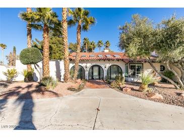 Spanish-style home with a large driveway and mature landscaping at 3990 Melody Ln, Las Vegas, NV 89108