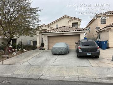 Two-car garage, covered car, and landscaped front yard at 6556 Mount Roy Ln, Las Vegas, NV 89156