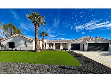 Single story home with a two-car garage, artificial turf, and palm trees at 2250 Shaw Cir, Las Vegas, NV 89117