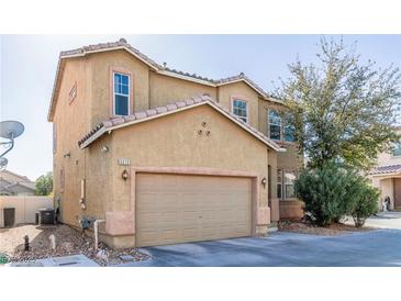 Two-story house with tan exterior, two-car garage, and landscaping at 5373 Sleeping Cat St, Las Vegas, NV 89122