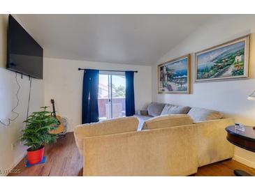 Bright living room with hardwood floors, large sectional sofa, and sliding glass door to balcony at , Las Vegas, NV 89147