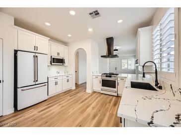 Bright kitchen boasts white cabinets, stainless steel appliances, and a modern black range hood at 10282 Country Flats Ln, Las Vegas, NV 89135