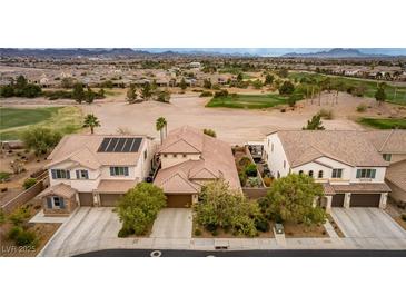 Aerial view of three houses with solar panels, landscaping, and a golf course in the background at 1172 Via Della Costrella, Henderson, NV 89011