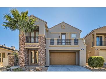 Two-story home showcasing neutral stucco, stacked stone, balcony, decorative trim, arched entry, two-car garage and mature palm tree at 217 Via Luna Rosa Ct, Henderson, NV 89011