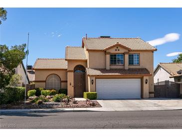 Two-story house with a beige exterior, a white garage door, and landscaping at 3817 W Red Coach Ave, North Las Vegas, NV 89031