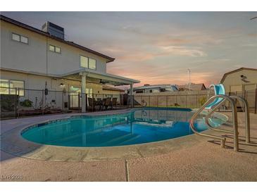 Inviting backyard pool with slide and covered patio area, perfect for outdoor entertaining and relaxation under a colorful sky at 4008 Snead Dr, Las Vegas, NV 89107