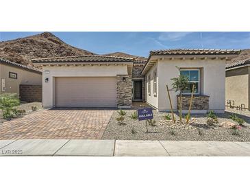 Charming single-story home with a two-car garage, stone accents, and a desert-landscaped front yard at 65 Ibiza Lake Dr, Henderson, NV 89011