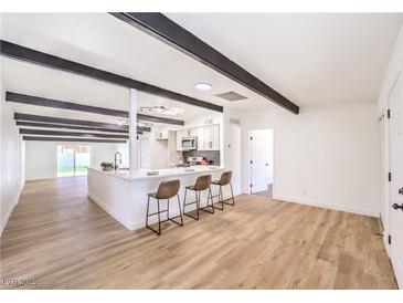 Open-concept living space with wood floors, kitchen island, and decorative beams at 701 N Yale St, Las Vegas, NV 89107