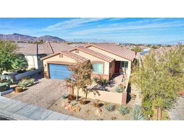 Tan house with blue garage door, desert landscaping, and mountain views at 1290 El Solindo Ln, Henderson, NV 89002