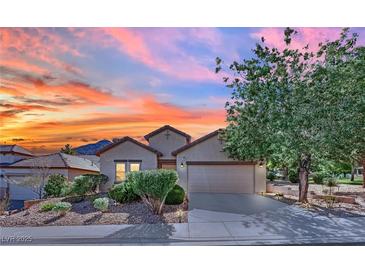 Charming single-story home featuring a well-manicured front yard and a two-car garage at sunset at 725 Pacific Cascades Dr, Henderson, NV 89012