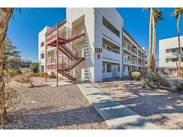Exterior view of a two-story building with red metal stairs and landscaping at 1361 E University Ave # 209, Las Vegas, NV 89119