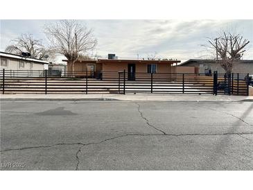 Tan house with a black metal fence and a spacious front yard at 5069 Hallet Dr, Las Vegas, NV 89122