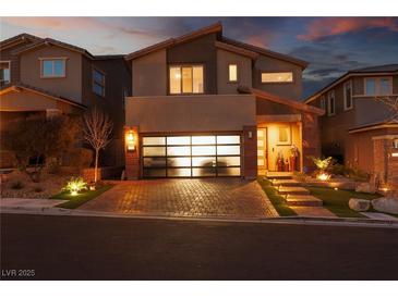 Charming two-story home featuring a modern glass garage door and inviting brick-paved driveway at 10936 White Alder Pl, Las Vegas, NV 89138