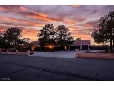 Single-story home with a landscaped yard, driveway, and a beautiful sunset in the background at 8365 Hauck St, Las Vegas, NV 89139