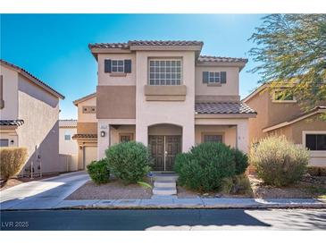 Two-story house with a tan exterior, double doors, and landscaping at 5023 Tunnel Falls Dr, Las Vegas, NV 89141