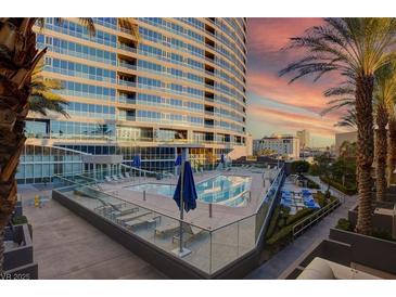 Stunning pool with lounge chairs with high rise building in the background at sunset at 4565 Dean Martin Dr # 102, Las Vegas, NV 89103