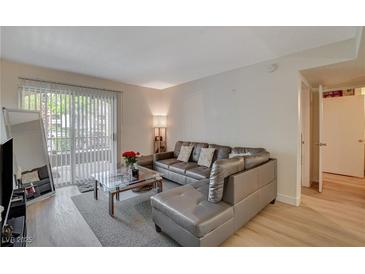 Comfortable living room featuring a sleek leather sofa, glass coffee table, and bright natural light from the large windows at 7885 W Flamingo Rd # 1037, Las Vegas, NV 89147