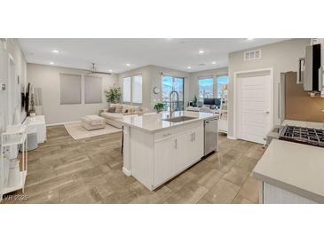 Modern, open kitchen featuring stainless steel appliances, a large island, and an adjacent living space with neutral decor at 11250 Hidden Peak Ave # 208, Las Vegas, NV 89135