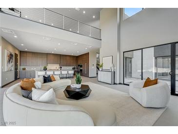 Expansive living room featuring a curved sofa, modern coffee table, and a balcony view at 1469 Dragon Stone Pl, Henderson, NV 89012