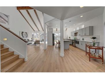 Bright open-concept living room and kitchen with vaulted ceilings and wood beam accents at 8941 Diamond Falls Dr, Las Vegas, NV 89117