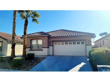 Tan house with tile roof, two-car garage, and desert landscaping at 3317 Barada Heights Ave, North Las Vegas, NV 89081