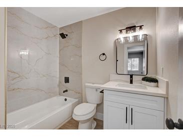 Modern bathroom featuring a tub with marble-style tile surround and a vanity with white cabinets at 4512 Mark Ave, Las Vegas, NV 89108