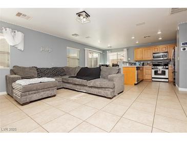 Open-concept living room featuring tile flooring and a large, comfortable gray sectional sofa at 6356 Blue Twilight Ct, Las Vegas, NV 89108