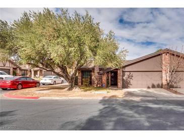 Brick house with a two-car garage and mature landscaping at 6520 Brushwood Ln, Las Vegas, NV 89107