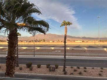 A picturesque view showcasing the landscape with palm trees, a highway, distant mountains, and a partly cloudy sky at 7732 Hand Woven Ct, Las Vegas, NV 89149