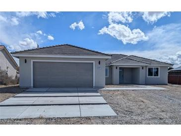 Charming single-story home featuring a two-car garage, tiled roof, and neutral color palette against a cloudy sky at 121 Comstock St, Pahrump, NV 89048