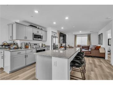 Modern kitchen features granite countertops, stainless steel appliances, grey cabinets and an island with bar stool seating at 2827 Blue Mosaic Ln # 3, Las Vegas, NV 89183