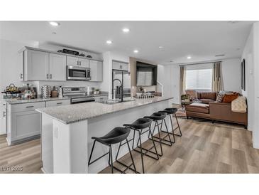 Bright kitchen features a large island with seating, granite countertops and stainless steel appliances at 2827 Blue Mosaic Ln # 3, Las Vegas, NV 89183