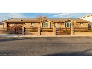 Charming brick home featuring solar panels, a secure gate, and well-maintained landscaping at 4410 E Boston Ave, Las Vegas, NV 89104