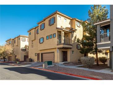 Inviting townhome with tan stucco, brown shutters and garage, in a well-maintained community at 5940 Palmilla St # 9, North Las Vegas, NV 89031