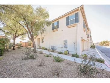 Tan two-story townhome with attached garage and landscaped yard at 7332 Marble Lake St # 103, Las Vegas, NV 89149