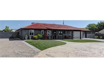 Charming gray home with a red tile roof, well-manicured lawn, and a circular driveway at 8880 W Ann Rd, Las Vegas, NV 89149