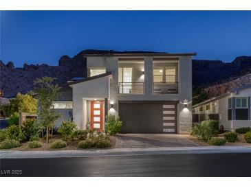 Modern two-story home with a minimalist design, balcony, desert landscaping and mountain views at twilight at 1945 Canyon Highlands Dr, Henderson, NV 89052