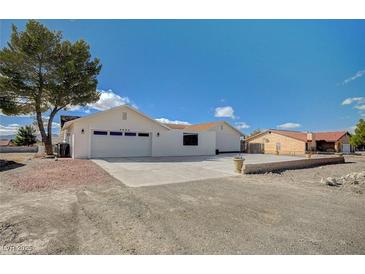 White single-story house with a two-car garage and landscaped yard at 2690 S Dandelion St, Pahrump, NV 89048