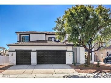Two-story home showcasing a well-maintained lawn, black garage doors, and a neutral color scheme at 4871 Charlemagne Ave, Las Vegas, NV 89130