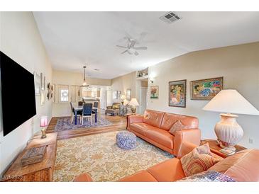 Spacious living room featuring hardwood floors, comfortable leather sofas, and a large TV at 5105 Kingsbridge Dr, Las Vegas, NV 89130