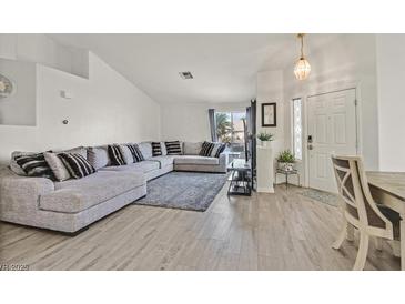 Bright living room featuring a large sectional sofa, wood floors, and view to front door at 5915 Ablette Ave, Las Vegas, NV 89122