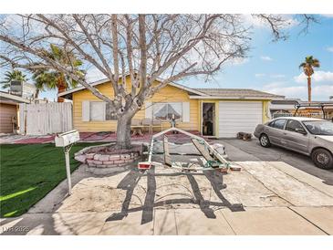 Charming single-story home with a yellow exterior, complemented by a well-maintained front yard and mature trees at 6409 Youngmont Ave, Las Vegas, NV 89103